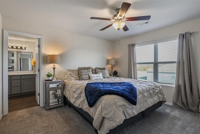 bedroom featuring ensuite bathroom, ceiling fan, and dark carpet