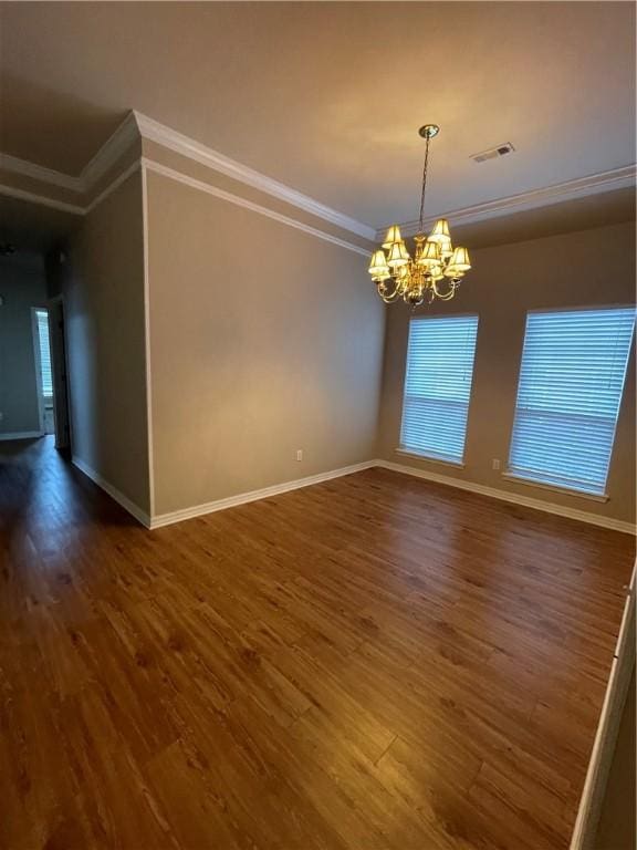 spare room featuring a notable chandelier, dark hardwood / wood-style flooring, and crown molding