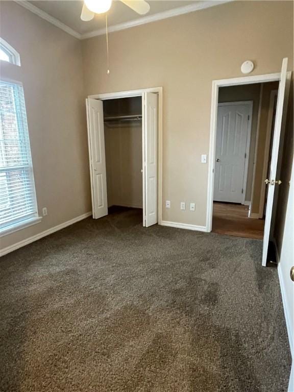 unfurnished bedroom featuring a closet, dark carpet, ceiling fan, and ornamental molding