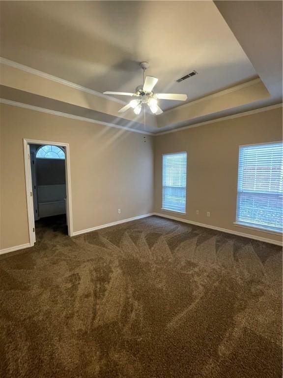 carpeted empty room featuring a raised ceiling, a wealth of natural light, ceiling fan, and ornamental molding