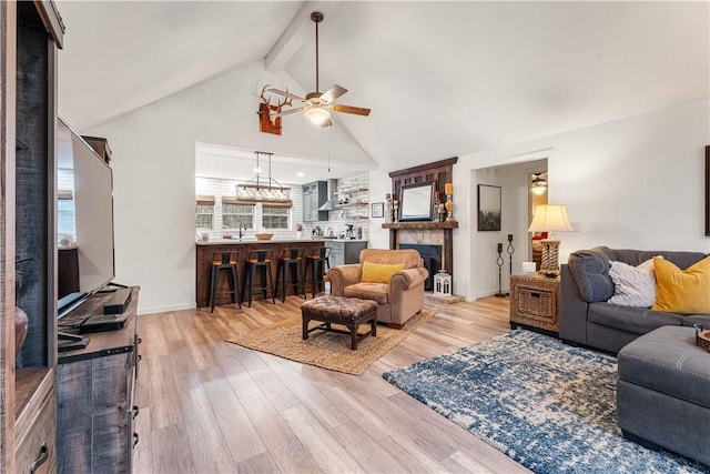 living room featuring beam ceiling, ceiling fan, high vaulted ceiling, and light wood-type flooring