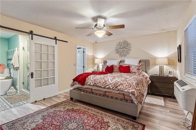 bedroom with ceiling fan, a barn door, and light wood-type flooring