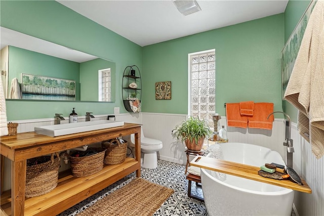 bathroom with a tub to relax in, toilet, and vanity