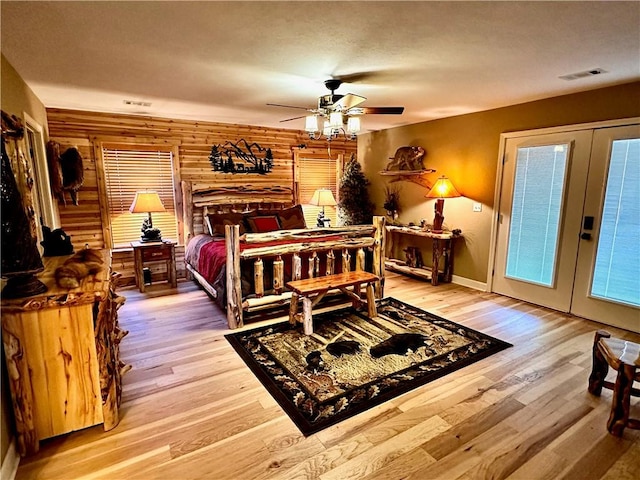 bedroom with hardwood / wood-style floors, ceiling fan, wood walls, and access to exterior