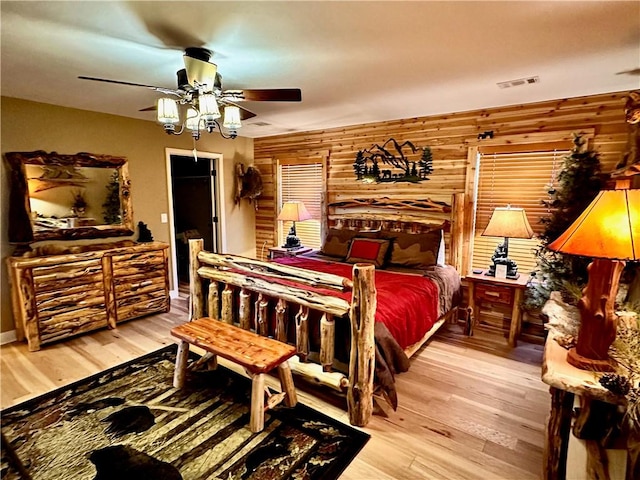 bedroom featuring light hardwood / wood-style flooring, ceiling fan, and wooden walls