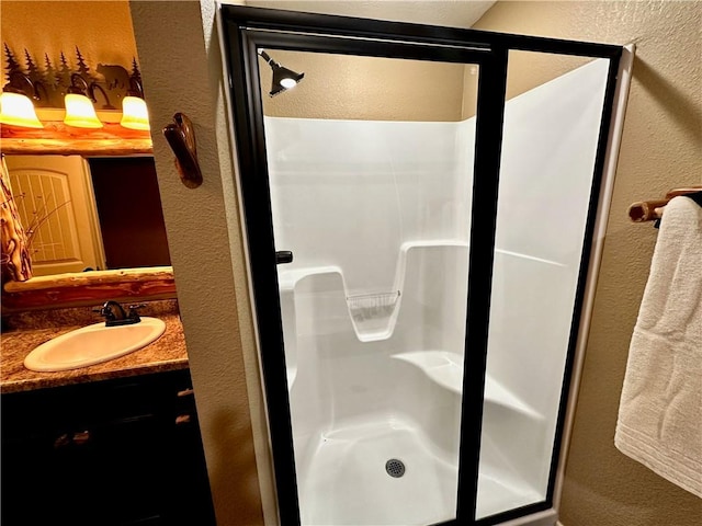 bathroom featuring a shower with door and vanity