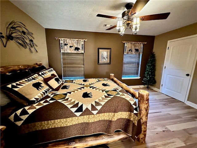 bedroom with a textured ceiling, light hardwood / wood-style flooring, and ceiling fan