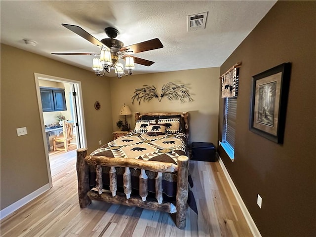 bedroom featuring ceiling fan, a textured ceiling, and light wood-type flooring