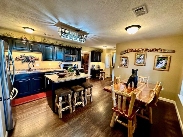 329 Bradley Ridge Rd, Marshall, AR 72650 - kitchen featuring stainless steel appliances, a center island, a textured ceiling, a breakfast bar, and dark wood-type flooring