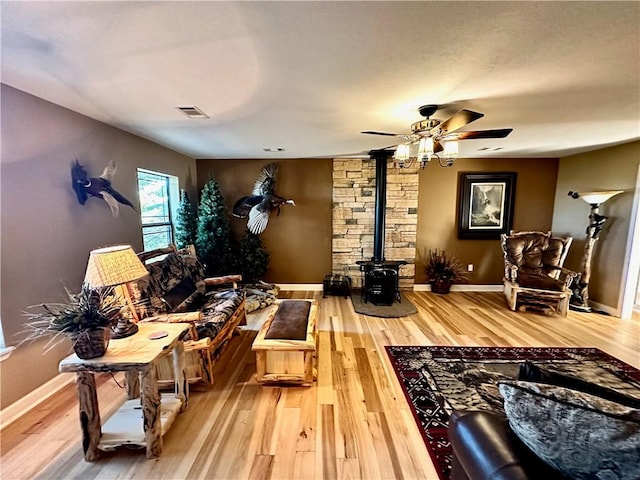 sitting room featuring hardwood / wood-style flooring, a wood stove, and ceiling fan