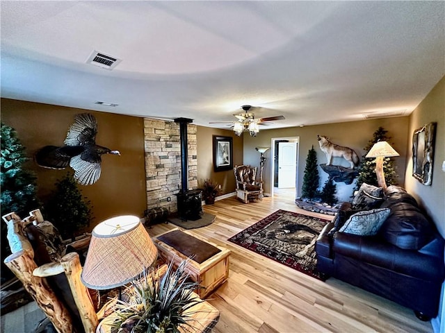 living room with a wood stove, ceiling fan, and hardwood / wood-style flooring