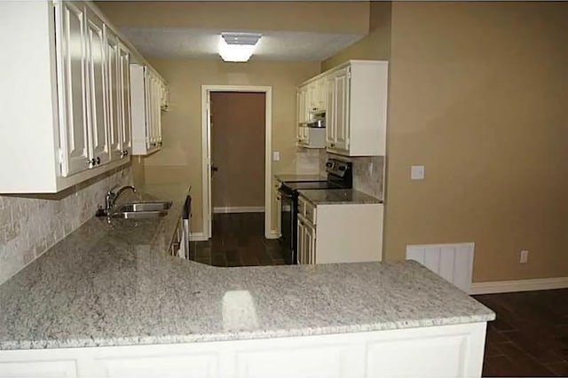 kitchen with kitchen peninsula, black range with electric cooktop, white cabinets, and sink