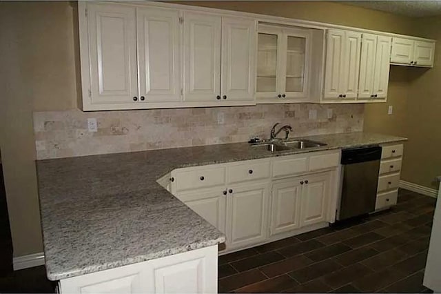 kitchen featuring backsplash, light stone counters, stainless steel dishwasher, sink, and white cabinetry