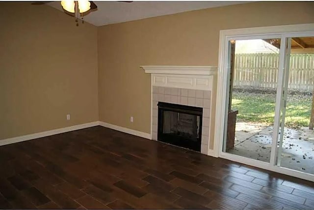 unfurnished living room featuring a tiled fireplace, ceiling fan, and dark hardwood / wood-style floors