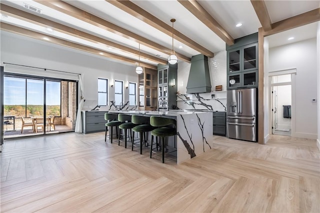 kitchen with visible vents, high end fridge, a breakfast bar, gray cabinets, and custom range hood