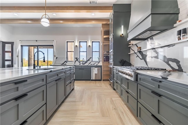 kitchen featuring gray cabinets, a sink, wall chimney range hood, decorative backsplash, and light stone countertops
