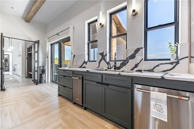 kitchen with beam ceiling, gray cabinets, light countertops, and stainless steel dishwasher