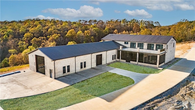 view of front facade featuring stucco siding, a view of trees, a sunroom, and metal roof