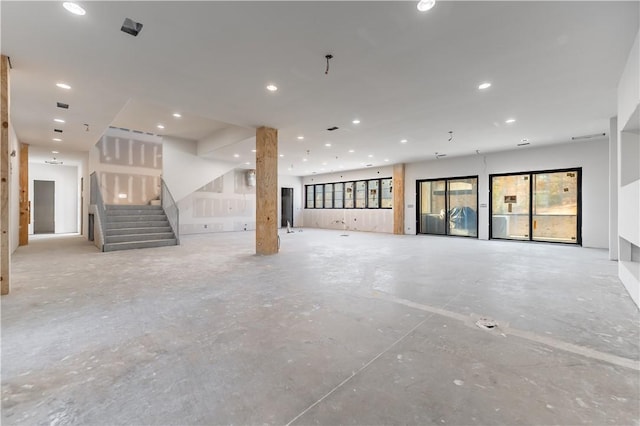unfurnished living room featuring stairway, recessed lighting, and concrete floors