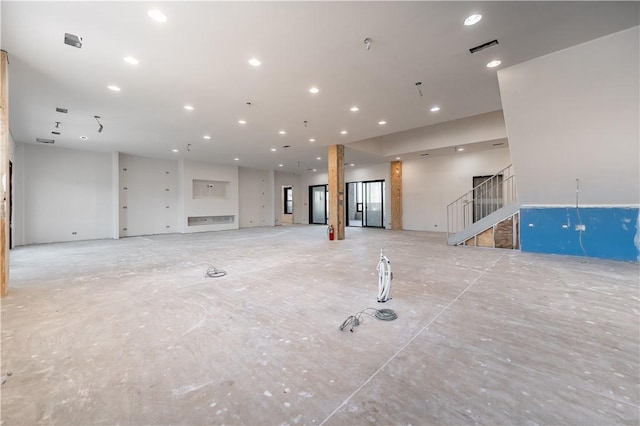 unfurnished living room featuring recessed lighting, visible vents, and stairs