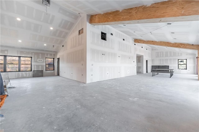 unfurnished living room featuring beam ceiling, high vaulted ceiling, and concrete flooring