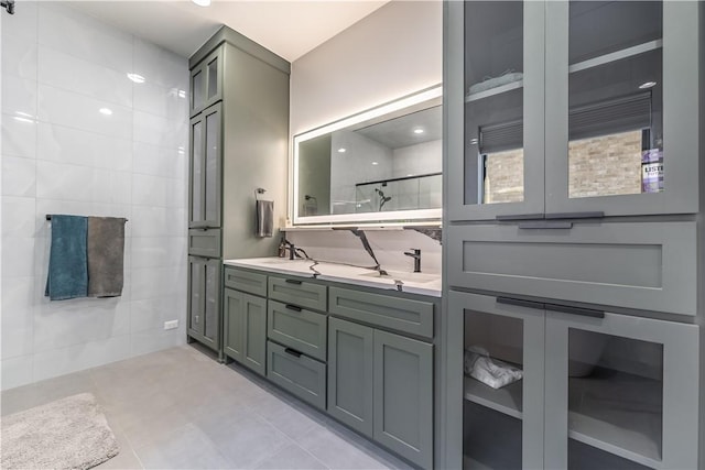 bathroom featuring double vanity, tile walls, walk in shower, and a sink