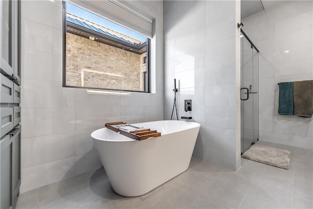 full bathroom with a soaking tub, a shower stall, and tile walls