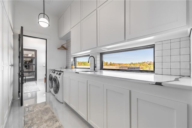 laundry room featuring a healthy amount of sunlight, cabinet space, a sink, marble finish floor, and independent washer and dryer