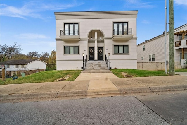 view of front of house with a balcony and a front lawn