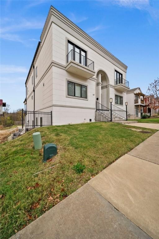 view of front of home with a balcony and a front lawn