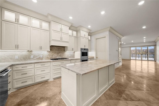 kitchen with a center island, white cabinets, crown molding, light stone countertops, and stainless steel appliances