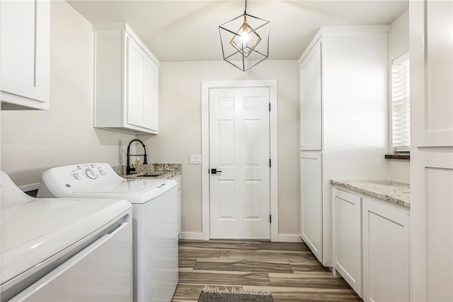 laundry room with cabinets, dark wood-type flooring, sink, washing machine and dryer, and a notable chandelier