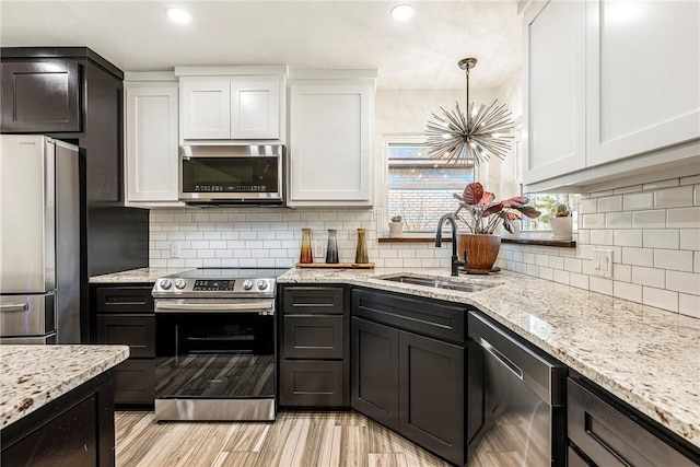 kitchen featuring sink, stainless steel appliances, tasteful backsplash, light stone counters, and white cabinets