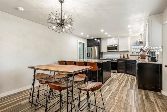 kitchen with light stone countertops, an inviting chandelier, stainless steel appliances, and a kitchen island