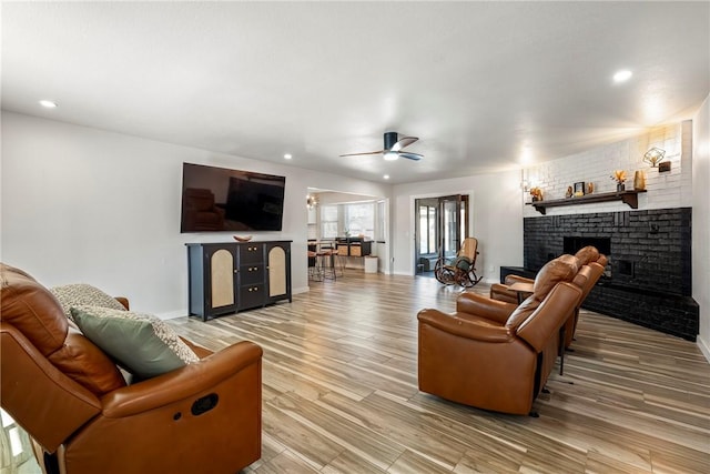 living room featuring ceiling fan, a fireplace, and hardwood / wood-style flooring