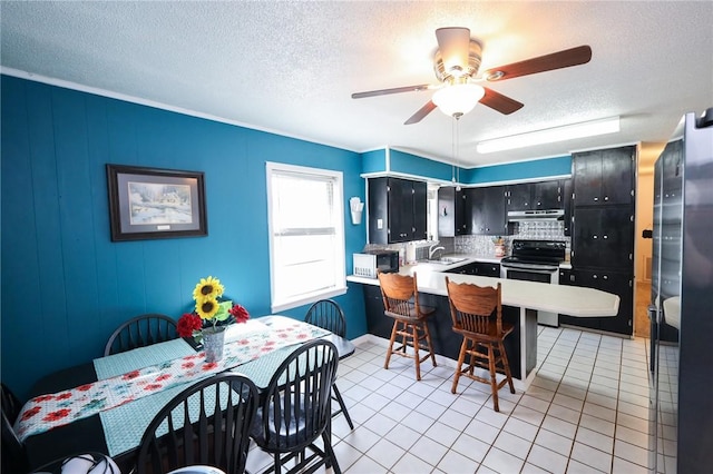 kitchen featuring kitchen peninsula, tasteful backsplash, stainless steel range with electric stovetop, sink, and light tile patterned floors