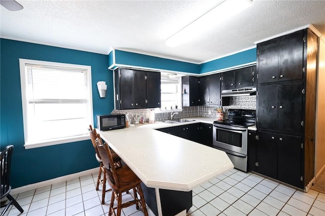 kitchen featuring a breakfast bar, stainless steel electric stove, sink, tasteful backsplash, and kitchen peninsula