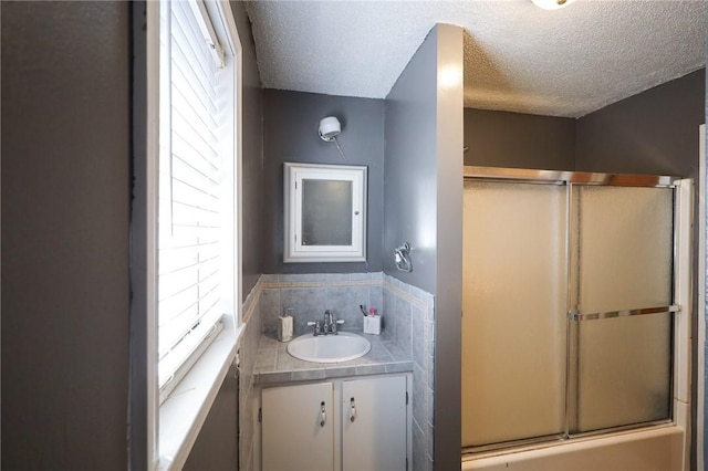 bathroom with vanity, shower / bath combination with glass door, and a textured ceiling