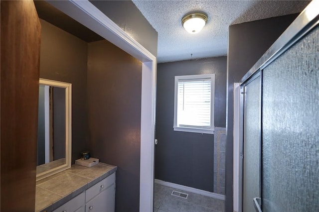 bathroom with tile patterned floors, an enclosed shower, and a textured ceiling