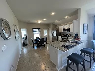 kitchen featuring kitchen peninsula, appliances with stainless steel finishes, a kitchen breakfast bar, sink, and white cabinets