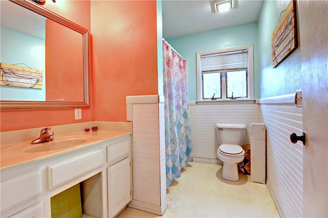 bathroom featuring a wainscoted wall, toilet, and vanity