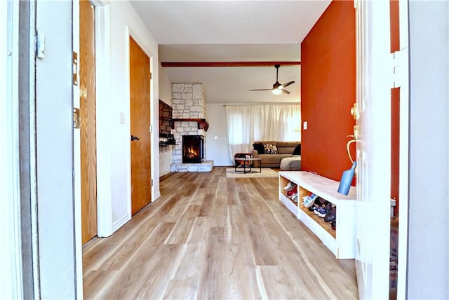 mudroom featuring a ceiling fan, a fireplace, and light wood finished floors