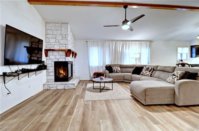 living room featuring vaulted ceiling with beams, ceiling fan, a stone fireplace, and light wood-type flooring