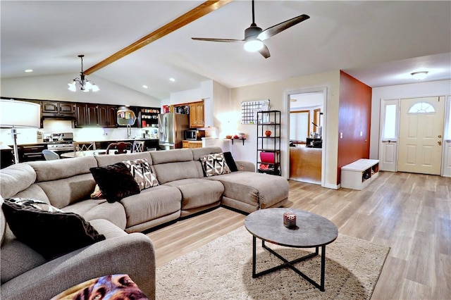 living room featuring ceiling fan with notable chandelier, vaulted ceiling with beams, and light hardwood / wood-style floors