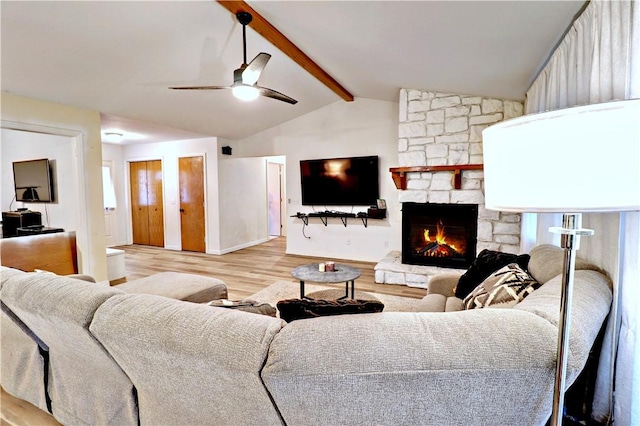 living area with light wood finished floors, baseboards, ceiling fan, lofted ceiling with beams, and a fireplace