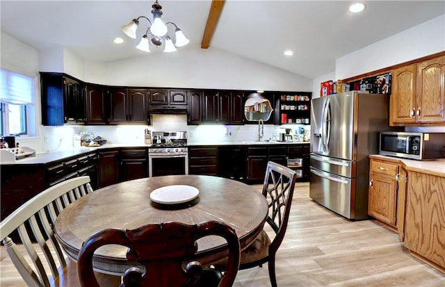 kitchen with light wood finished floors, under cabinet range hood, lofted ceiling with beams, appliances with stainless steel finishes, and a sink