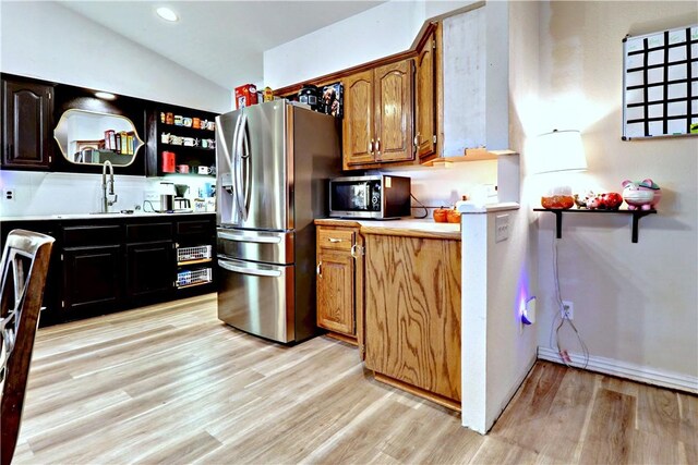 kitchen with sink, light wood-type flooring, lofted ceiling, and appliances with stainless steel finishes