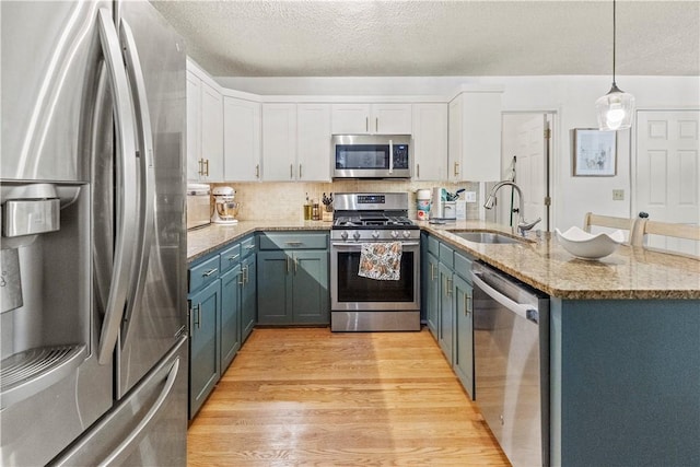 kitchen with white cabinets, light wood-style flooring, a sink, and appliances with stainless steel finishes