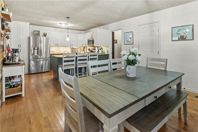 dining room with light wood-type flooring and a textured ceiling