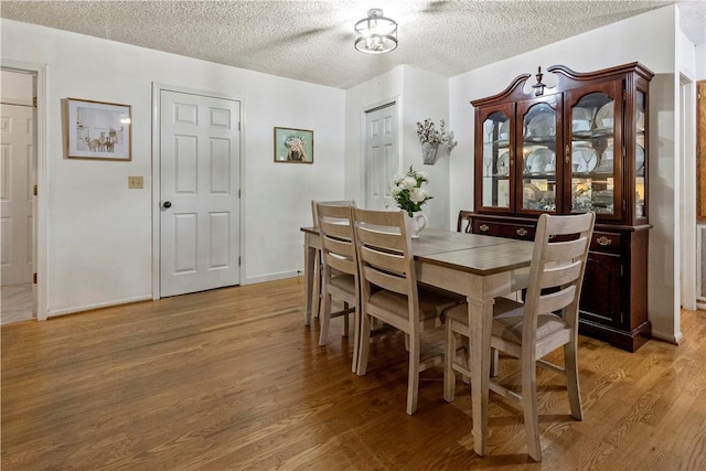 dining area featuring light wood-style floors and a textured ceiling